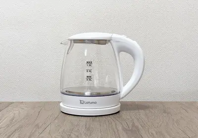 a white electric kettle sitting on a wooden table at tokyo mirai 3F in Tokyo