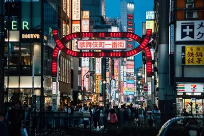 a busy city street with neon signs and people at Cava House in Tokyo