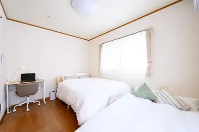 two beds in a room with a desk and a window at Nico Galleria Ōyama in Tokyo