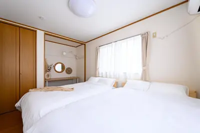 two white beds in a bedroom with a window at Nico Galleria Ōyama in Tokyo