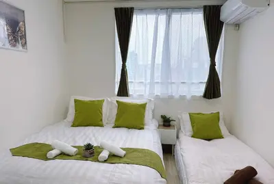 a bedroom with two beds with green pillows and a window at Joy \u4e1c\u4eac\u6674\u7a7a\u5854 in Tokyo