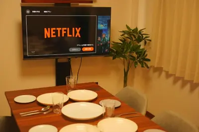 a table with white plates and a television on a wall at Wonderful stay TOKYO KURAMAE in Tokyo