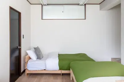 a bedroom with a green bed and white sheets at -Room MtFuji- Max 9 people 8 minutes to Shibuya 5 minutes to Shinjuku 1 minute to Harajuku 4 minutes walk from the station in Tokyo