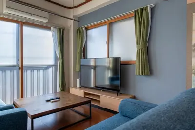 a living room with a tv and a blue couch at -Room MtFuji- Max 9 people 8 minutes to Shibuya 5 minutes to Shinjuku 1 minute to Harajuku 4 minutes walk from the station in Tokyo