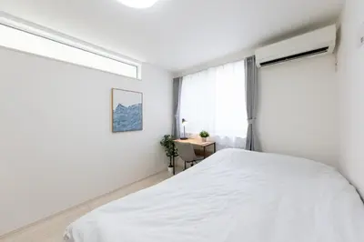 a white bedroom with a bed and a window at FINOA Residential Suite Takaido in Tokyo