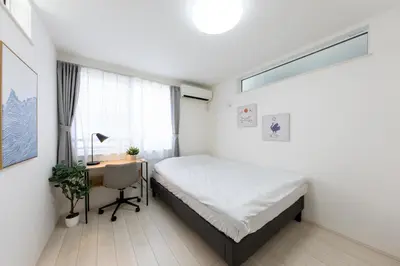 a bedroom with a bed and a desk and a window at FINOA Residential Suite Takaido in Tokyo