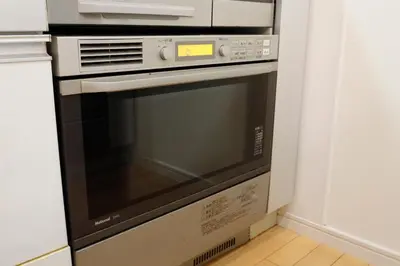 a microwave oven in a kitchen next to a wall at Dori Dori House Ebisu in Tokyo