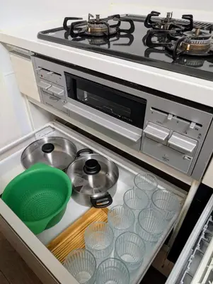 a stove top oven with dishes and pans in a drawer at \u6c60\u888b\u672c\u753a303 in Tokyo