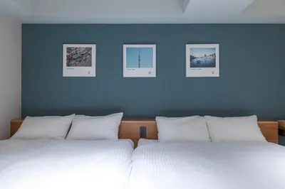 two beds in a bedroom with three pictures on the wall at 9Stay \u83ca\u5ddd in Tokyo
