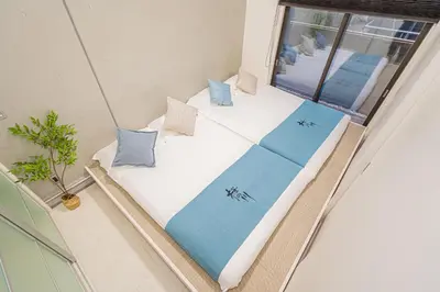 a room with a bed with blue pillows and a window at \u685c\u306e\u5ddd70-36\u6c60\u888b\u99c58\u5206\u949f 1DK\u5957\u623f max5\u4eba\u623f \u5bbd\u655e\u5b89\u9759 ikeburuko in Tokyo