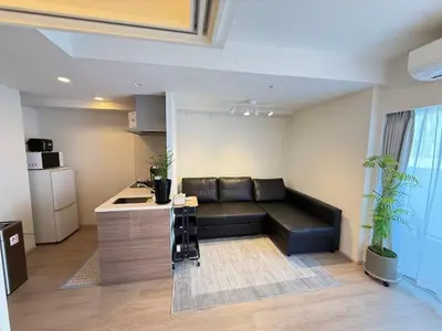 a living room with a black couch and a kitchen at Ying-Higashi Shinjuku-SJ0061 in Tokyo