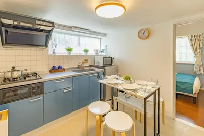 a kitchen with blue cabinets and a table with stools at Shinjuku two stations, three-bedroom apartment, 6 people, seven minutes from Higashi-Nakano station in Tokyo