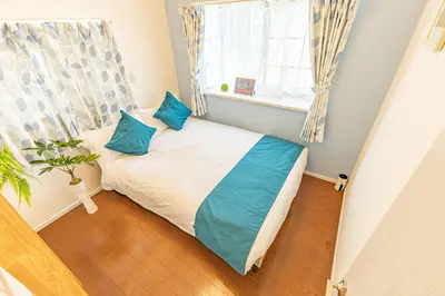 a small bedroom with a bed with blue pillows at Shinjuku two stations, three-bedroom apartment, 6 people, seven minutes from Higashi-Nakano station in Tokyo