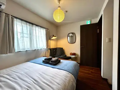 a bedroom with a large bed with a blue blanket at \u4e2d\u91ce\u99c5\u5357inn Nakano Station South Inn in Tokyo