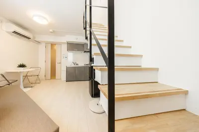 a living room with stairs and a kitchen at SJ Stay in Tokyo
