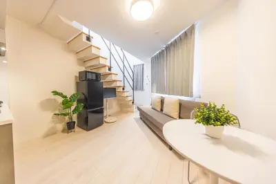 a living room with a staircase and a couch at SJ Stay in Tokyo