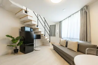 a living room with a couch and a spiral staircase at SJ Stay in Tokyo