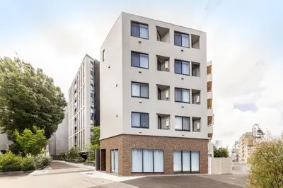 a tall white building with windows on a street at SJ Stay in Tokyo