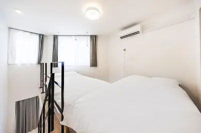 two beds in a room with white walls and windows at SJ Stay in Tokyo