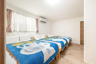 a bedroom with two beds with blue and white sheets at \u65b0\u5bbf\u307e\u306715\u5206 \u5f25\u751f\u753a\u306e\u6238\u5efa\u3066 in Tokyo