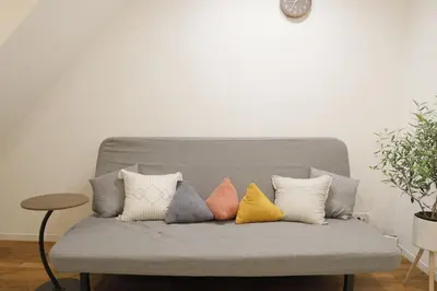 a gray couch with four different colored pillows on it at Dori Dori House Sumida in Tokyo