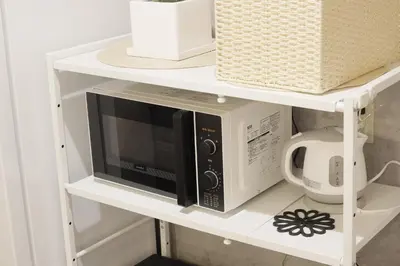a white shelf with a microwave on it at Dori Dori House Sumida in Tokyo