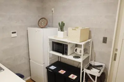 a microwave on a shelf next to a refrigerator at Dori Dori House Sumida in Tokyo