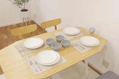 a wooden table with white plates and silverware on it at Dori Dori House Sumida in Tokyo