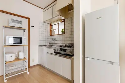 a small kitchen with white cabinets and a refrigerator at ntb\u5800\u52072\u4e01\u76eeESTA 2 in Tokyo