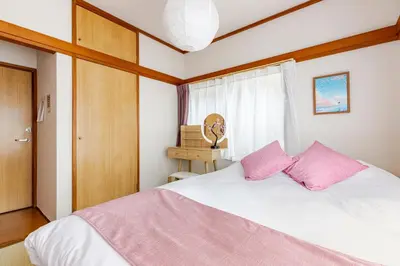 a bedroom with a white bed with pink pillows at ntb\u5800\u52072\u4e01\u76eeESTA 2 in Tokyo