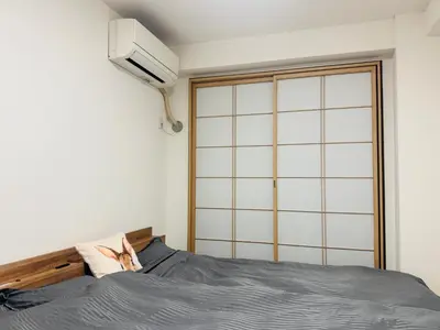 a bedroom with a bed and a wall mounted fan at B&B 103 under the clear sky Go straight to Narita 8 minutes on foot from Kinshicho Station 1 minute on foot from Asakusa and Skytree 50 minutes from Disneyland 1 minute from Monopolis in Tokyo