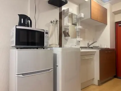 a kitchen with a microwave on top of a refrigerator at B&B 103 under the clear sky Go straight to Narita 8 minutes on foot from Kinshicho Station 1 minute on foot from Asakusa and Skytree 50 minutes from Disneyland 1 minute from Monopolis in Tokyo