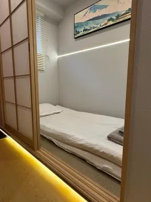a small room with a bed and a mirror at Minshuku 203 under the clear sky 8-minute walk from Kinshicho Station direct line to Narita Airport 50-minute walk from Disneyland and 1-minute walk from the mall in Tokyo