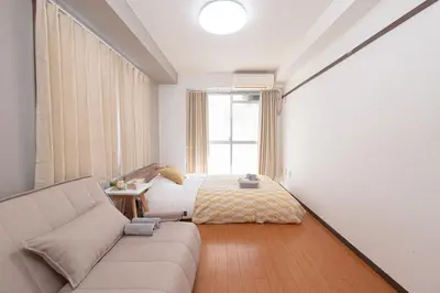 a bedroom with a bed and a couch and a window at Clear Sky Guesthouse 205 Direct to Narita Airport, 8-minute walk from Kinshicho Station, within walking distance of Asakusa and Clear Sky Tower, 50 minutes to Disneyland, 1 minute to the mall in Tokyo