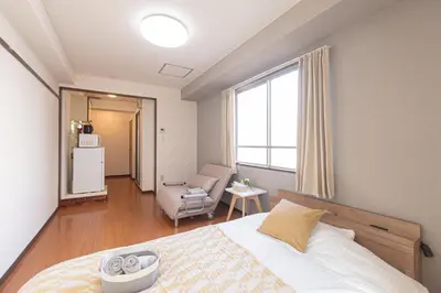 a bedroom with a bed and a chair and a window at Clear Sky Guesthouse 205 Direct to Narita Airport, 8-minute walk from Kinshicho Station, within walking distance of Asakusa and Clear Sky Tower, 50 minutes to Disneyland, 1 minute to the mall in Tokyo