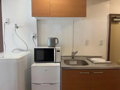 a small kitchen with a microwave and a sink at Clear Sky Guesthouse 305 Direct to Narita Airport, 8-minute walk from Kinshicho Station, within walking distance of Asakusa and Clear Sky Tower, 50 minutes to Disneyland, 1 minute to the mall in Tokyo