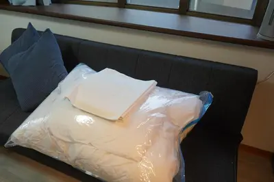 a couch covered in plastic with a book on it at \u6771\u4eac\u5927\u7530\u533a\u5e73\u548c\u5cf6\u30a2\u30d1\u30fc\u30c8\u30e1\u30f3\u30c8 in Tokyo
