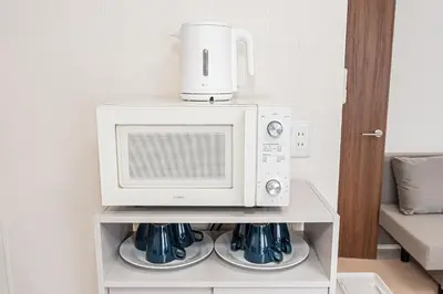 a microwave sitting on top of a shelf with cups at 67Apt Shinkoiwa in Tokyo