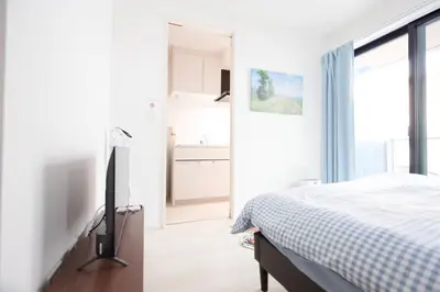 a white bedroom with a bed and a television at Tell House in Tokyo