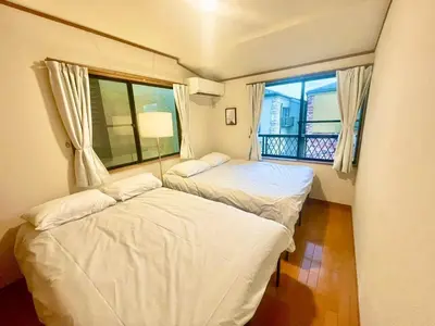 two beds in a room with a window at \u6e0b\u8c37\u533a\u306e\u4e00\u8ed2\u5bb6 80\u5e73\u7c73 3\u5bdd\u5ba46\u30d9\u30c3\u30c9 \u5e61\u30f6\u8c37\u99c5\u5f92\u6b695\u5206 \u65b0\u5bbf\u307e\u3067\u96fb\u8eca4\u5206 in Tokyo