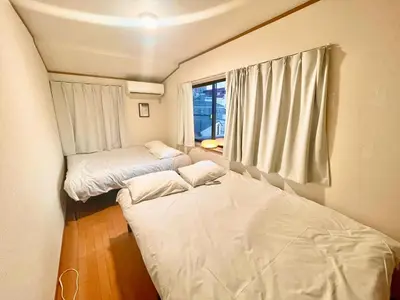 two beds in a small room with a window at \u6e0b\u8c37\u533a\u306e\u4e00\u8ed2\u5bb6 80\u5e73\u7c73 3\u5bdd\u5ba46\u30d9\u30c3\u30c9 \u5e61\u30f6\u8c37\u99c5\u5f92\u6b695\u5206 \u65b0\u5bbf\u307e\u3067\u96fb\u8eca4\u5206 in Tokyo