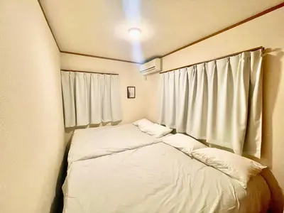 a small bedroom with two beds and a window at \u6e0b\u8c37\u533a\u306e\u4e00\u8ed2\u5bb6 80\u5e73\u7c73 3\u5bdd\u5ba46\u30d9\u30c3\u30c9 \u5e61\u30f6\u8c37\u99c5\u5f92\u6b695\u5206 \u65b0\u5bbf\u307e\u3067\u96fb\u8eca4\u5206 in Tokyo