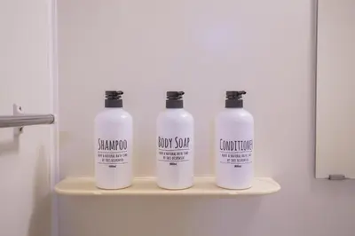 three bottles of shampoo sit on a shelf in a bathroom at \u6771\u4e2d\u91ce\u99c5\u5f92\u6b693\u5206 \u4ea4\u901a\u81f3\u4fbf \u4e0b\u753a\u30b0\u30eb\u30e1 \u5546\u5e97\u8857\u30b7\u30e7\u30c3\u30d4\u30f3\u30b0\u5bbf YoEh in Tokyo