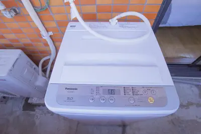 a washing machine with a white cord attached to a wall at \u6771\u4e2d\u91ce\u99c5\u5f92\u6b693\u5206 \u4ea4\u901a\u81f3\u4fbf \u4e0b\u753a\u30b0\u30eb\u30e1 \u5546\u5e97\u8857\u30b7\u30e7\u30c3\u30d4\u30f3\u30b0\u5bbf YoEh in Tokyo
