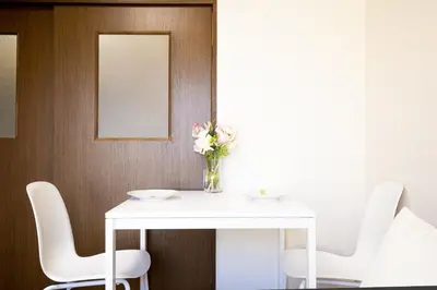 a white table with chairs and a vase of flowers on it at \u6771\u4e2d\u91ce\u99c5\u5f92\u6b693\u5206 \u4ea4\u901a\u81f3\u4fbf \u4e0b\u753a\u30b0\u30eb\u30e1 \u5546\u5e97\u8857\u30b7\u30e7\u30c3\u30d4\u30f3\u30b0\u5bbf YoEh in Tokyo
