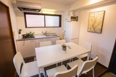 a small kitchen with a white table and chairs at \u5317\u65b0\u5bbf\u5f92\u6b693\u5206 \u4ea4\u901a\u81f3\u4fbf \u4e0b\u753a\u30b0\u30eb\u30e1 \u5546\u5e97\u8857\u30b7\u30e7\u30c3\u30d4\u30f3\u30b0\u5bbf S02c in Tokyo
