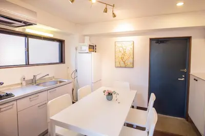a kitchen with a white table and a white refrigerator at \u5317\u65b0\u5bbf\u5f92\u6b693\u5206 \u4ea4\u901a\u81f3\u4fbf \u4e0b\u753a\u30b0\u30eb\u30e1 \u5546\u5e97\u8857\u30b7\u30e7\u30c3\u30d4\u30f3\u30b0\u5bbf S02c in Tokyo