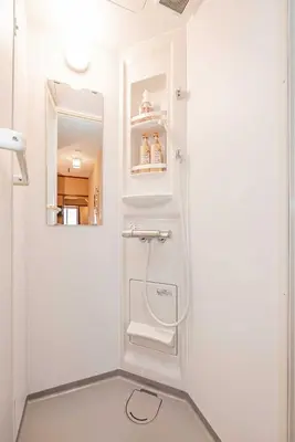a white bathroom with a shower and a mirror at Hotel Ginnan in Tokyo