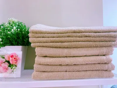 a stack of towels on a shelf with a vase of flowers at Shinjuku House-1 in Tokyo