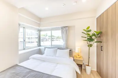 a white bedroom with a bed and a window at Parkview, 3min by Train to Shibuya, 5min by Train to Shinjuku in Tokyo